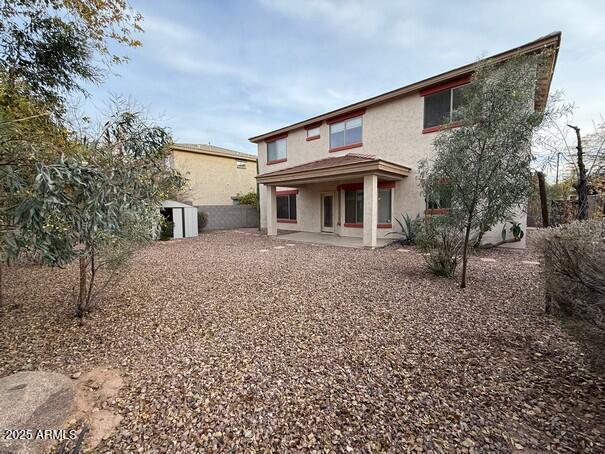 back of property with a shed and a patio area