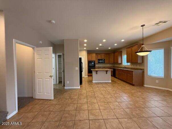 kitchen with a kitchen island, sink, hanging light fixtures, light tile patterned floors, and black appliances