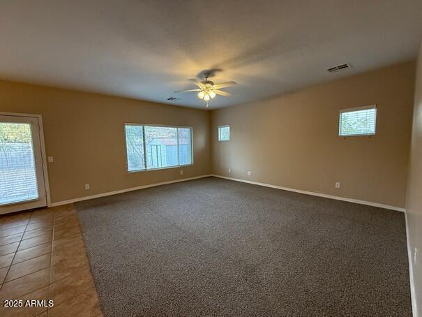 unfurnished room with plenty of natural light, dark tile patterned flooring, and ceiling fan