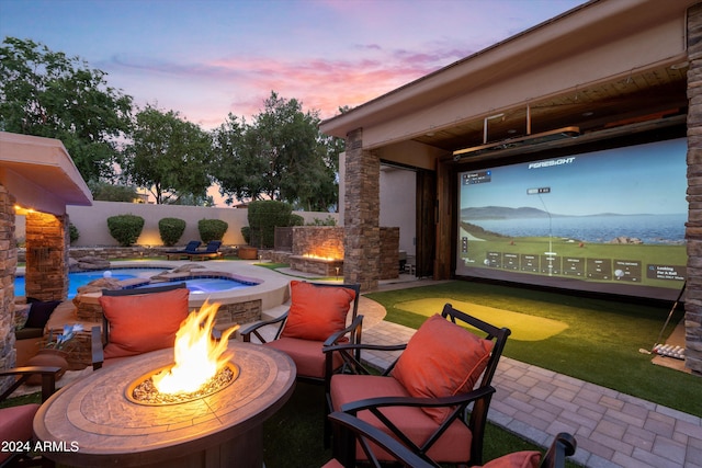 patio terrace at dusk with an in ground hot tub and an outdoor fire pit