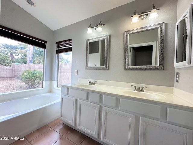 bathroom featuring vaulted ceiling, tile patterned floors, a tub, and vanity