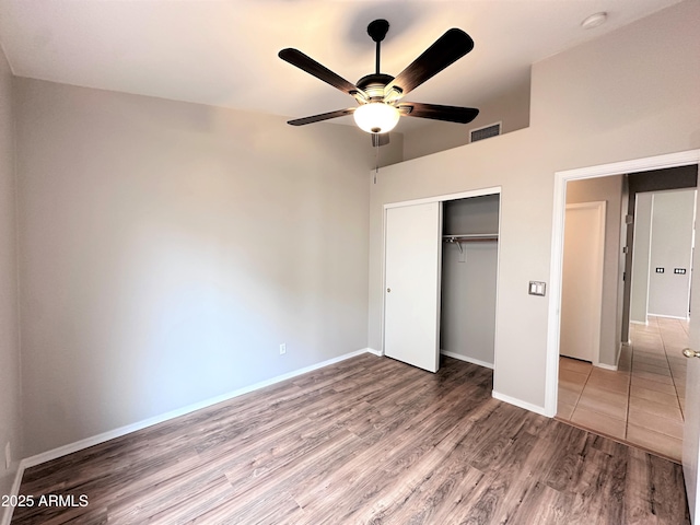 unfurnished bedroom featuring ceiling fan, wood-type flooring, and a closet