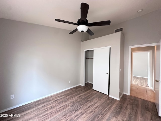 unfurnished bedroom featuring ceiling fan, a closet, and dark wood-type flooring