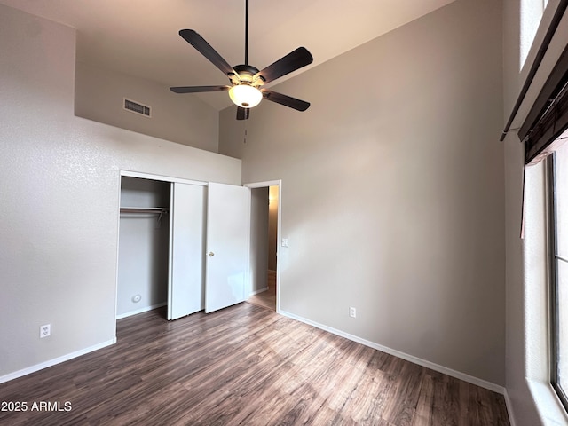 unfurnished bedroom with ceiling fan, a closet, dark hardwood / wood-style floors, and high vaulted ceiling