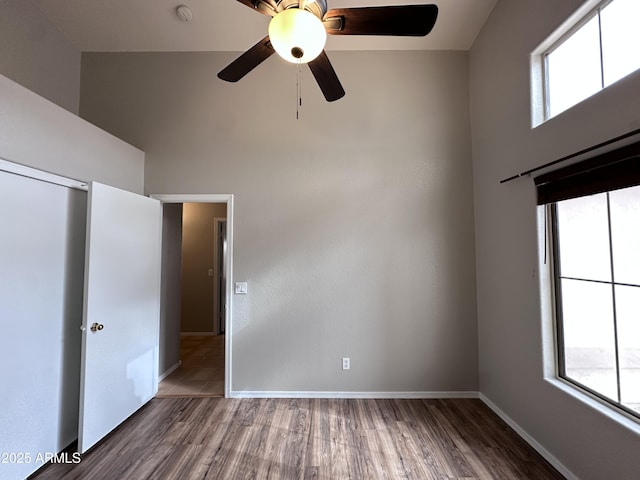 interior space featuring ceiling fan, a closet, a towering ceiling, and hardwood / wood-style floors