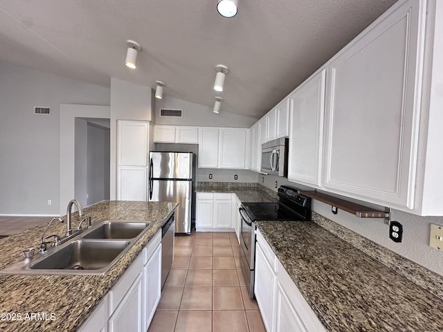 kitchen featuring light tile patterned floors, white cabinetry, stainless steel appliances, lofted ceiling, and sink