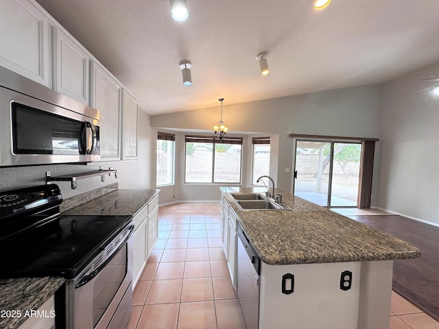 kitchen with white cabinetry, stainless steel appliances, sink, light tile patterned flooring, and a center island with sink