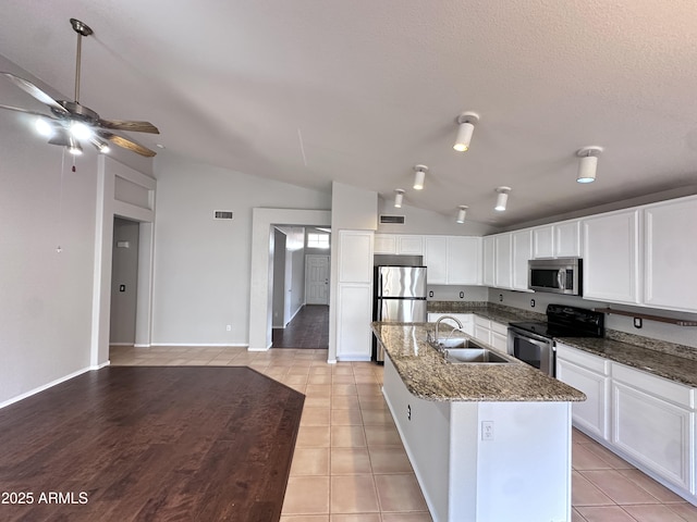 kitchen with a center island with sink, appliances with stainless steel finishes, lofted ceiling, white cabinets, and sink