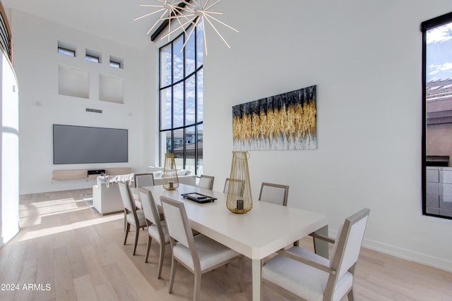 dining area with a notable chandelier, a high ceiling, and light wood-type flooring