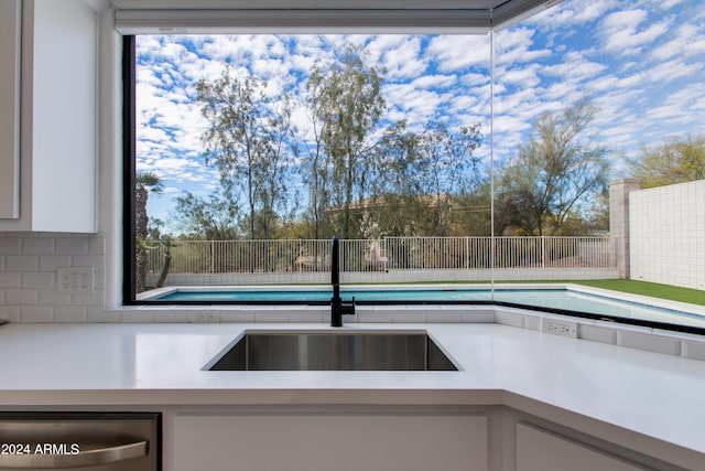 kitchen featuring tasteful backsplash, dishwasher, sink, and white cabinets