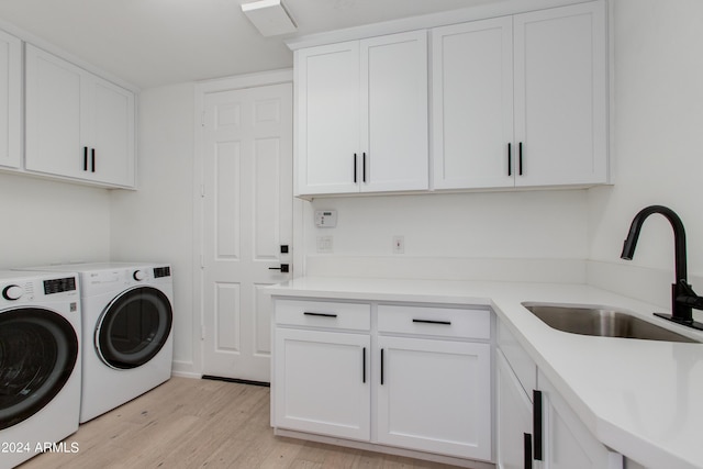 laundry room featuring cabinets, independent washer and dryer, sink, and light hardwood / wood-style floors