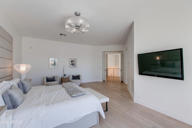 bedroom featuring a notable chandelier and light hardwood / wood-style flooring