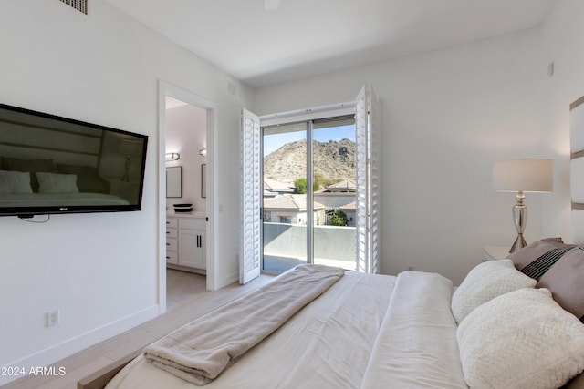 bedroom featuring a mountain view, access to exterior, connected bathroom, and light hardwood / wood-style floors