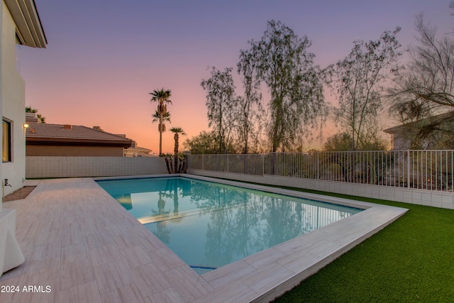 pool at dusk featuring a patio