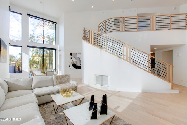 living room featuring a towering ceiling, wood-type flooring, and plenty of natural light