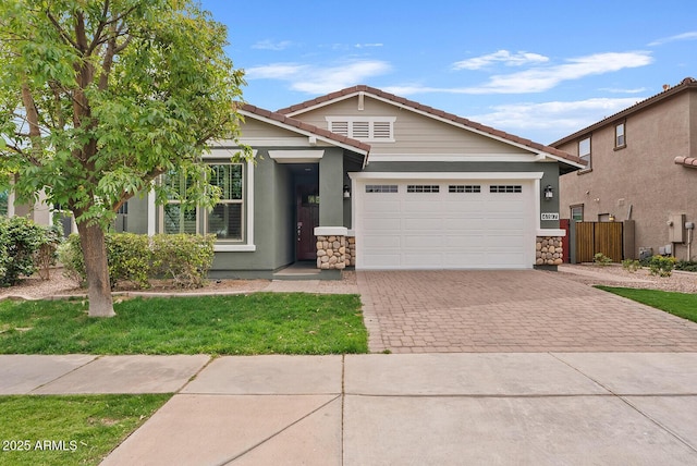 view of front of property with stucco siding, a tile roof, decorative driveway, stone siding, and an attached garage