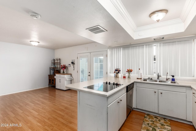 kitchen with light wood-type flooring, dishwasher, kitchen peninsula, sink, and a tray ceiling