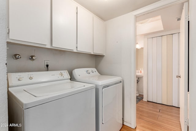 laundry area featuring cabinets, separate washer and dryer, and light wood-type flooring