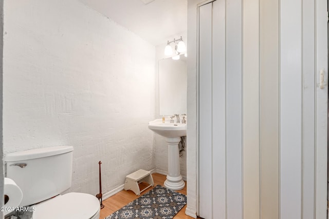 bathroom with toilet, sink, hardwood / wood-style floors, and vaulted ceiling