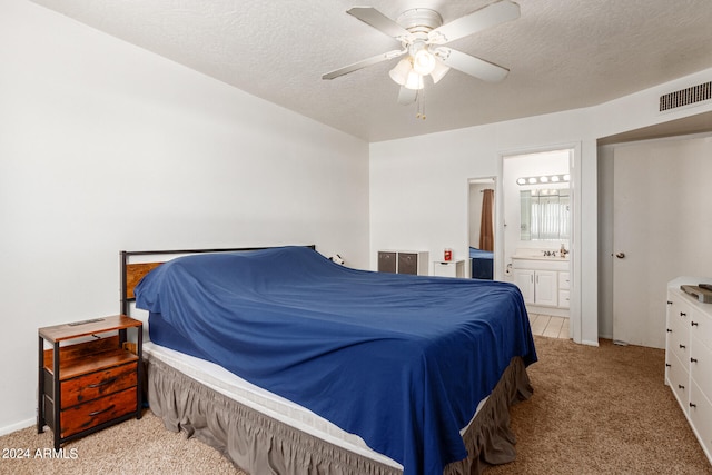 carpeted bedroom featuring a textured ceiling, ensuite bathroom, and ceiling fan