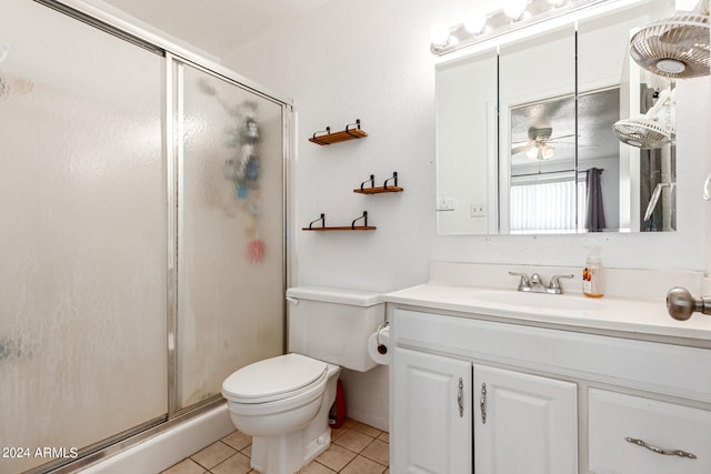 bathroom featuring a shower with door, tile patterned floors, toilet, ceiling fan, and vanity