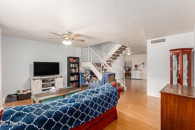 living room with hardwood / wood-style floors, ceiling fan, and a textured ceiling