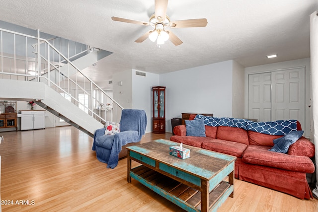 living room featuring wood-type flooring, a textured ceiling, and ceiling fan