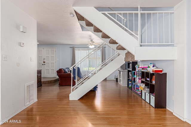 staircase with ceiling fan and hardwood / wood-style flooring