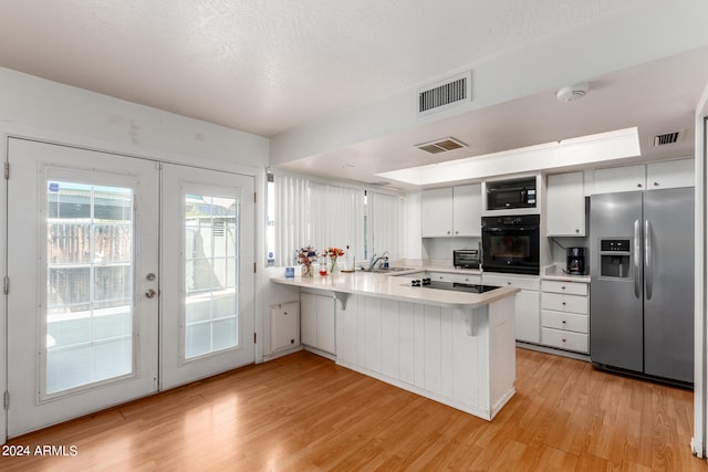 kitchen with black appliances, kitchen peninsula, white cabinetry, and light hardwood / wood-style floors