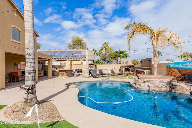 view of swimming pool featuring pool water feature, area for grilling, exterior fireplace, and a patio area