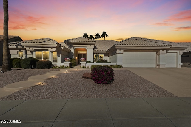 prairie-style house with a garage, driveway, a tiled roof, and stucco siding