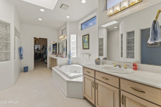 full bath with a jetted tub, a spacious closet, vanity, and recessed lighting