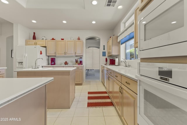 kitchen featuring white appliances, visible vents, light brown cabinets, a sink, and recessed lighting