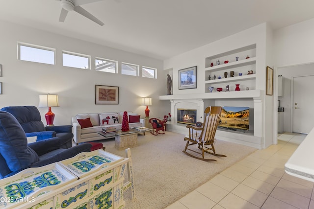 living room with ceiling fan, built in shelves, tile patterned flooring, and a glass covered fireplace