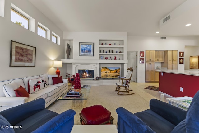 living area with built in shelves, recessed lighting, visible vents, and a tiled fireplace