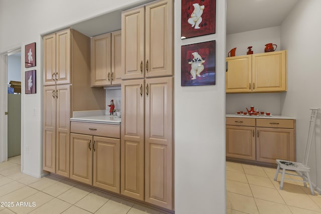 kitchen featuring light tile patterned floors, light brown cabinets, baseboards, and light countertops