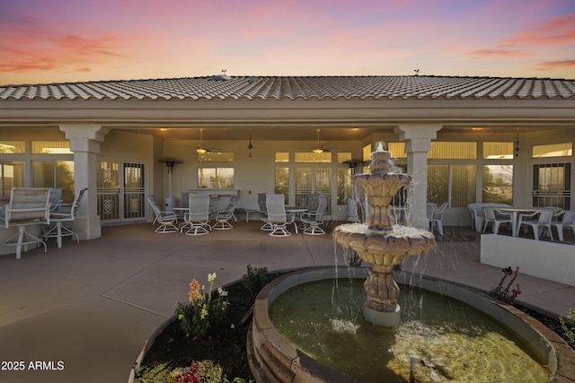 rear view of property with french doors, a patio area, outdoor dining space, and a tile roof