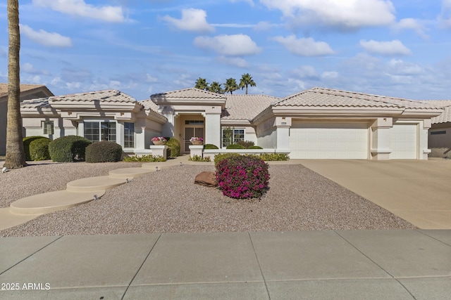 view of front of home with concrete driveway, a tiled roof, an attached garage, and stucco siding