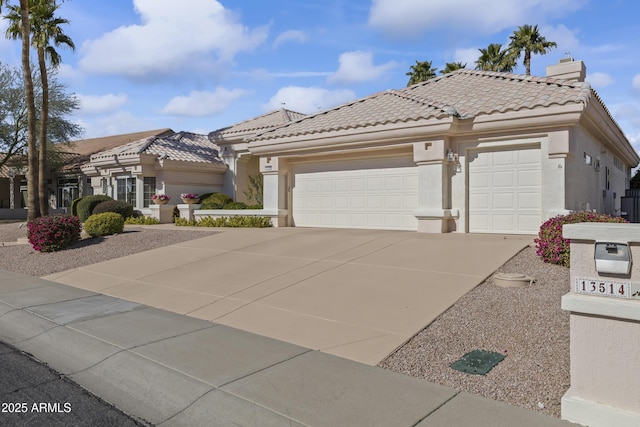 view of front of property with an attached garage, a tile roof, concrete driveway, stucco siding, and a chimney