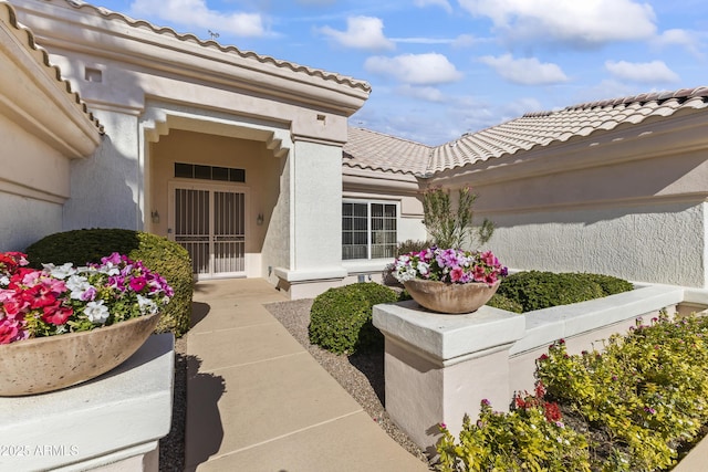 doorway to property featuring a tiled roof and stucco siding