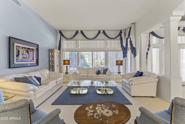 carpeted living area featuring visible vents and ornate columns