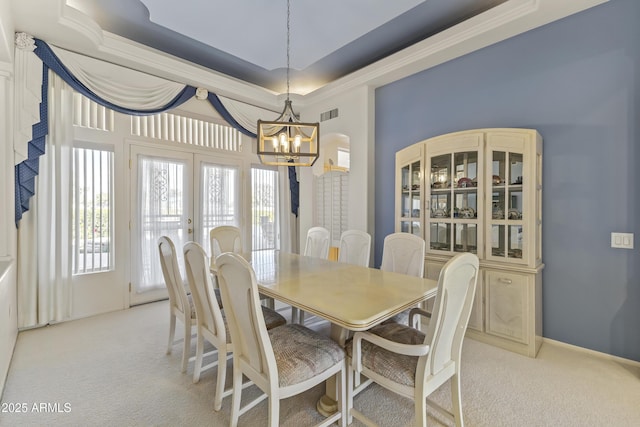 dining room with light carpet, visible vents, a raised ceiling, and french doors