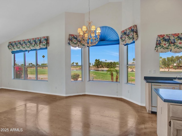 15377 W Catalina Ct, Goodyear, AZ 85395 - unfurnished dining area with a chandelier, healthy amount of natural light, wood finished floors, and high vaulted ceiling