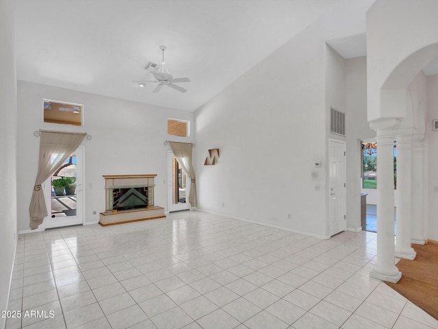 15377 W Catalina Ct, Goodyear, AZ 85395 - unfurnished living room with a towering ceiling, ornate columns, a fireplace with raised hearth, ceiling fan, and light tile patterned floors