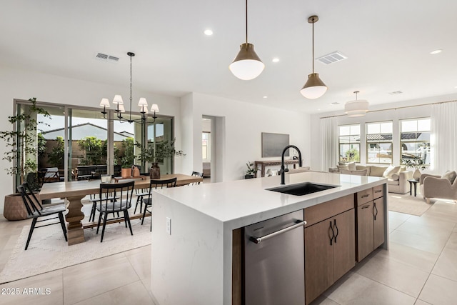 kitchen with sink, light tile patterned floors, hanging light fixtures, and a center island with sink