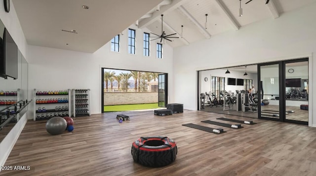 gym with hardwood / wood-style flooring, high vaulted ceiling, and ceiling fan