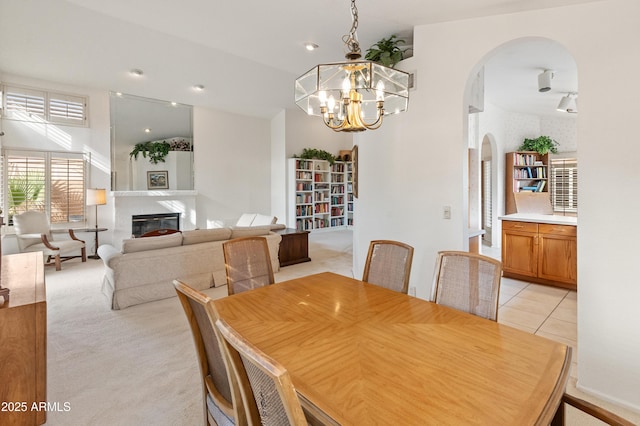 tiled dining room featuring an inviting chandelier and a high end fireplace