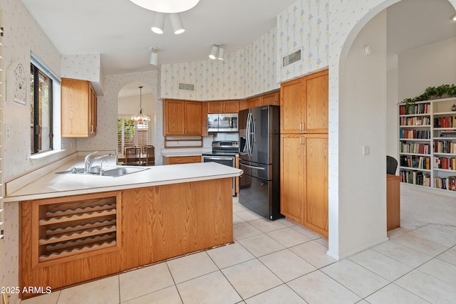 kitchen with stainless steel appliances, sink, hanging light fixtures, kitchen peninsula, and light tile patterned flooring