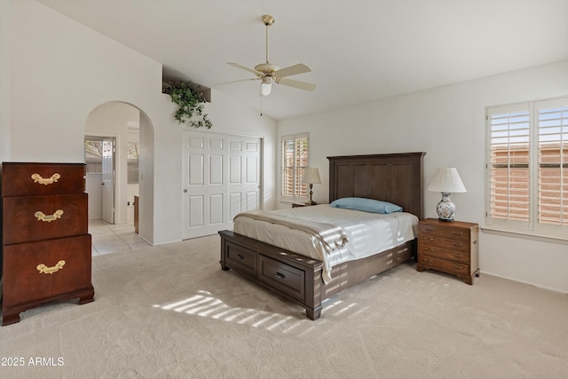 carpeted bedroom with multiple windows, a closet, vaulted ceiling, and ceiling fan