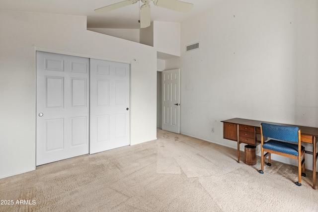 carpeted bedroom with a closet, ceiling fan, and high vaulted ceiling